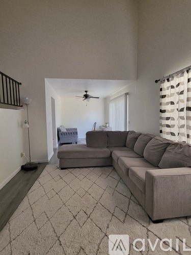 A living room with a grey sofa and a ceiling fan.