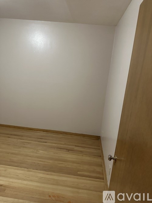 A wooden staircase with a white wall and a brown door.