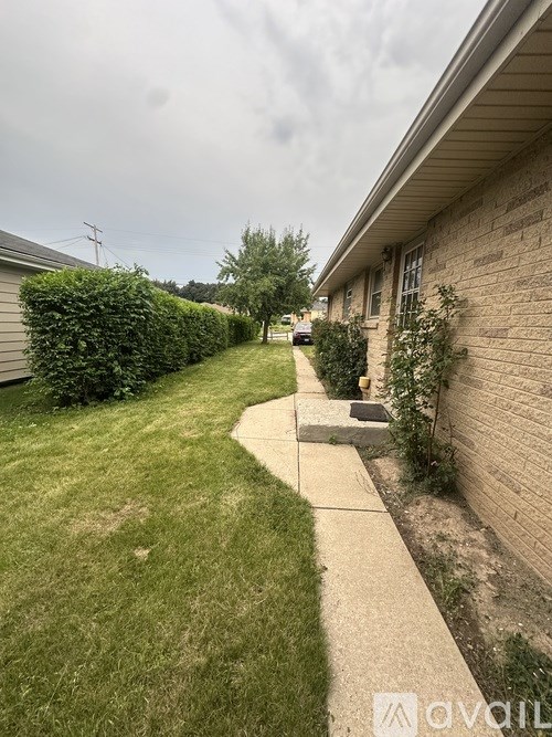 A residential area with a well-maintained lawn and a sidewalk.