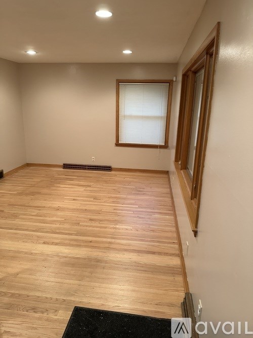 A room with wooden flooring and a window with blinds.