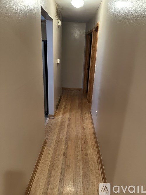 A long hallway with wood floors and white walls.