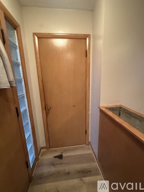 A brown door is in a white room.