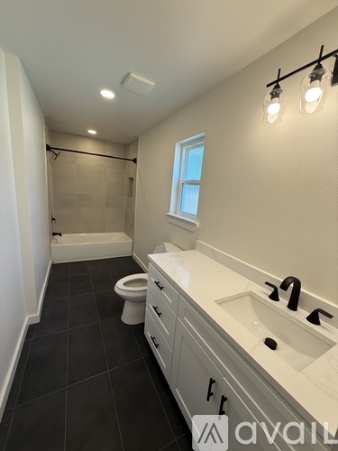 A bathroom with a toilet, sink, and a window.