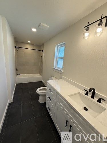 A bathroom with a toilet, sink, and a window.