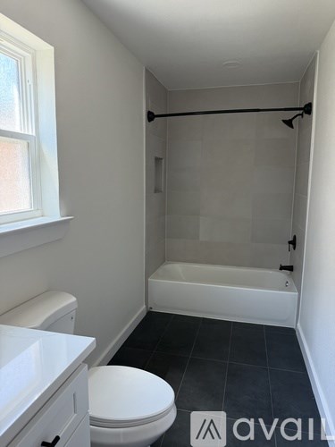 A bathroom with a toilet, a tub, and a window.