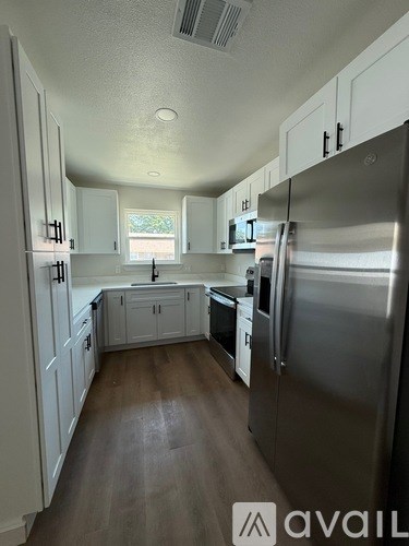 A kitchen with white cabinets and a stainless steel refrigerator.