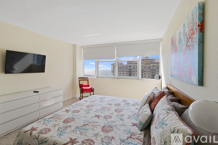 A bedroom with a bed, a chair, and a painting on the wall.
