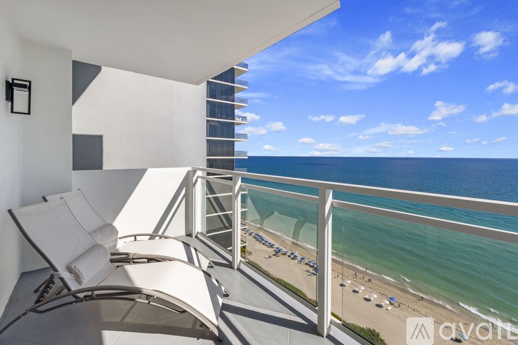 A balcony with chairs overlooking a beach.