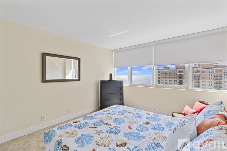 A bedroom with a bed, dresser, and a window with blinds.