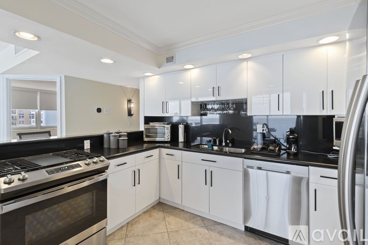 A modern kitchen with white cabinets and black countertops.