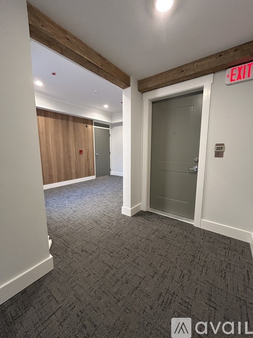 A hallway with a wooden floor leads to a kitchen area.