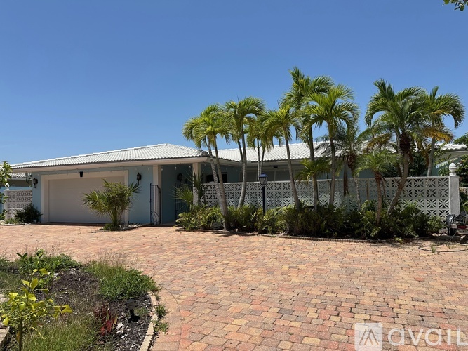 A house with a driveway and palm trees in front.