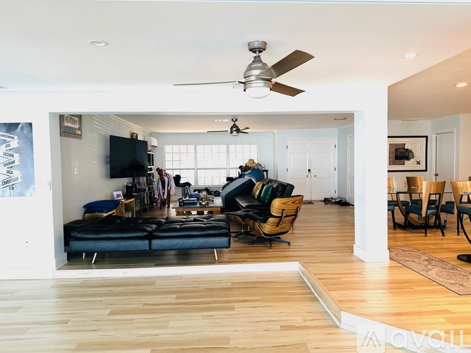 A living room with a black couch and a ceiling fan.