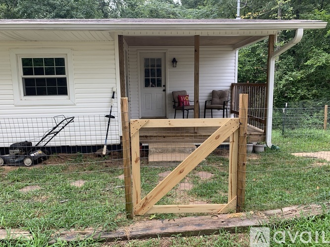 A small white house with a porch and a wooden gate.