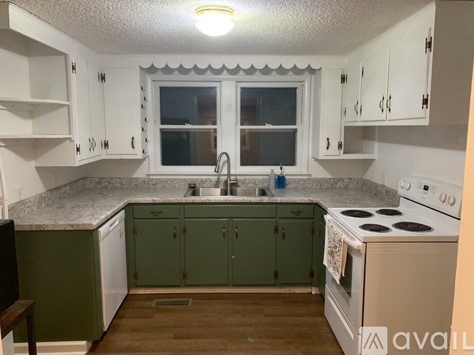 A kitchen with white cabinets and green countertops.