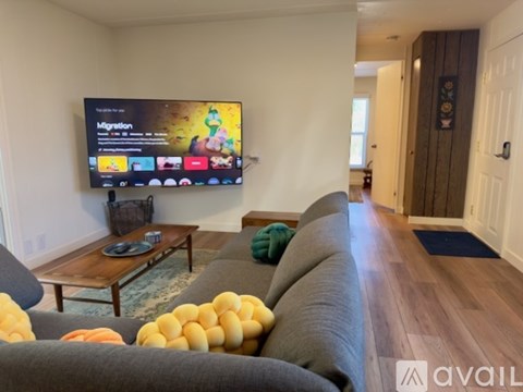 A living room with a television displaying the word "Migration" and a row of yellow balls on the couch.