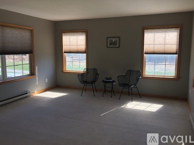 A room with two chairs and a table in front of two windows.