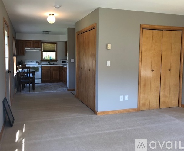 A kitchen with a dining table and chairs is visible through the open door.