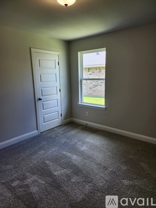 A room with a carpeted floor, a door, and a window.