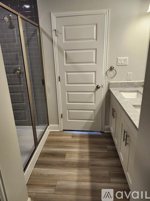 A white door is in a bathroom with a glass shower door.