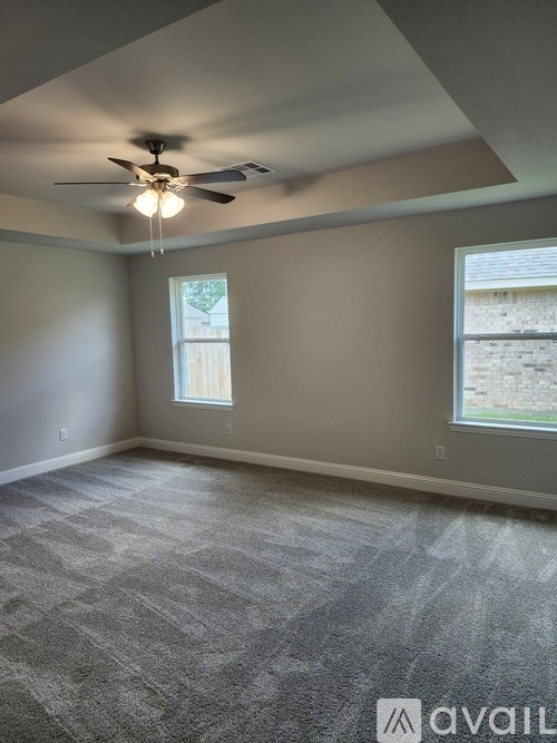 A room with a ceiling fan and carpeted floor.