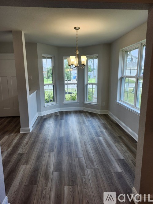 A room with wooden flooring and a chandelier.