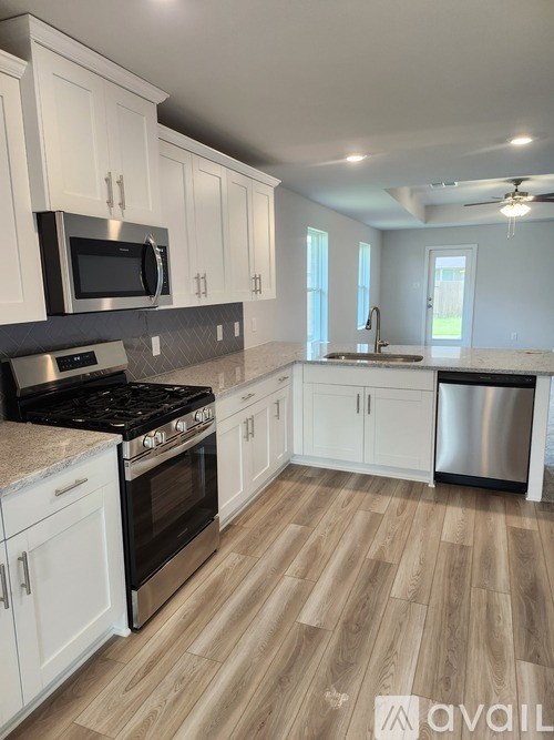 A kitchen with white cabinets and a wooden floor.