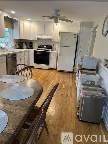 A kitchen with white appliances and wooden floors.