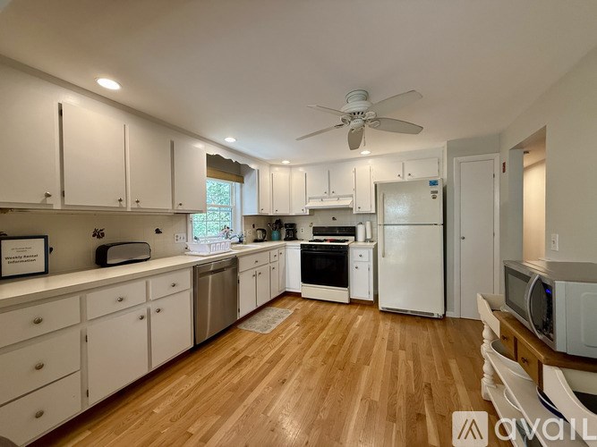 A kitchen with white cabinets and a wooden floor.