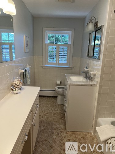 A bathroom with a toilet, sink, and a window with blinds.