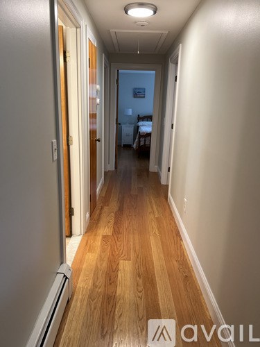 A long hallway with wood floors and white walls.