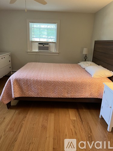 A bedroom with a bed, nightstand, and window.