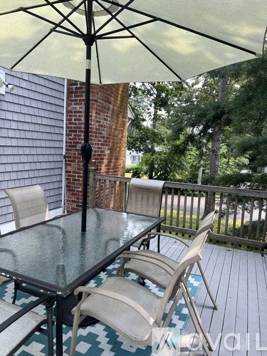 A glass table with chairs and an umbrella on a deck.