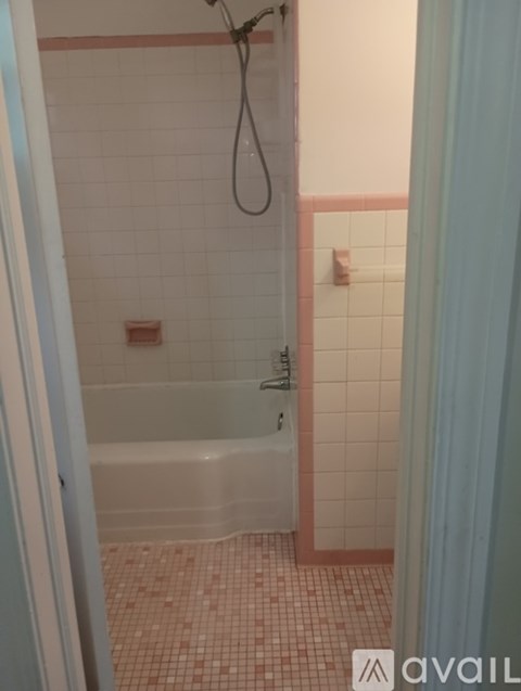 A bathroom with a white tub and pink tiles.