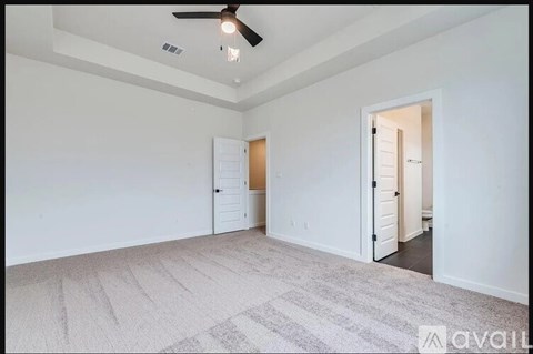 A room with a carpeted floor and a ceiling fan.