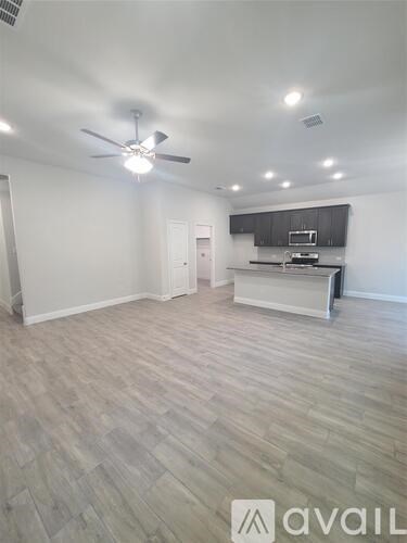 A spacious room with a ceiling fan and lighting fixtures.