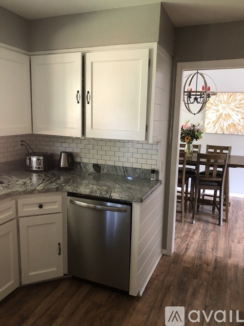 A kitchen with white cabinets and a marble countertop.