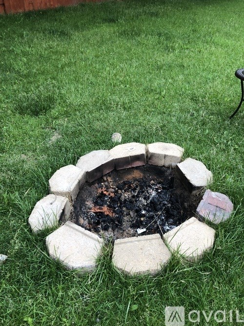 A fire pit with a blackened interior sits in a grassy area.