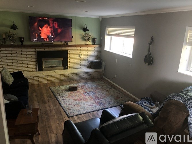 A living room with a fireplace and a flat screen TV mounted above it.