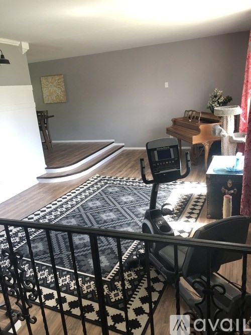 A living room with a rug, a chair, a table, and a piano.