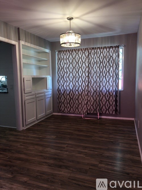 A room with wooden flooring and a chandelier hanging from the ceiling.