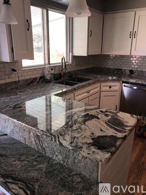A kitchen with a marble countertop and white cabinets.