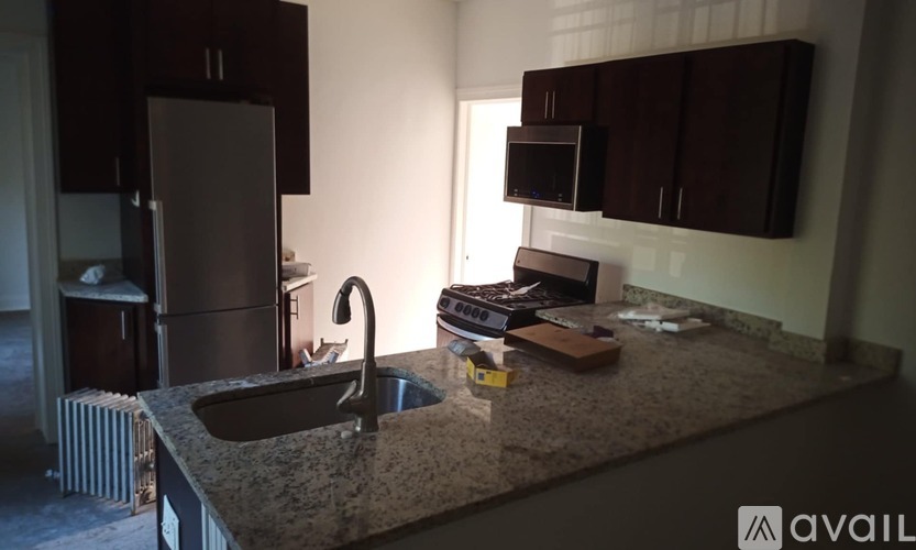 A kitchen with granite countertops and dark brown cabinets.