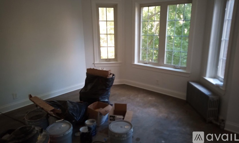 A room with a window and a person sitting on a chair.