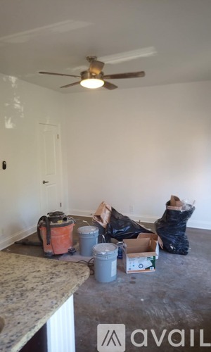A room with a ceiling fan and a few items on the floor.