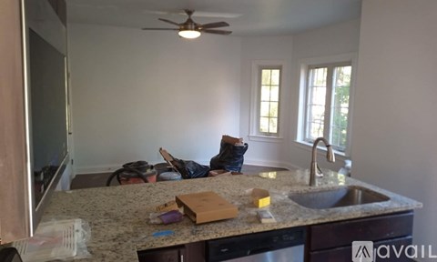 A kitchen counter with a sink, a fan, and a window.
