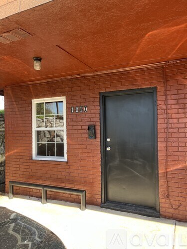 A red brick house with a black door and a window with a white frame.