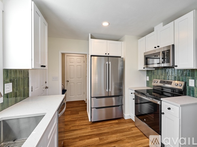 A kitchen with white cabinets and a stainless steel refrigerator.