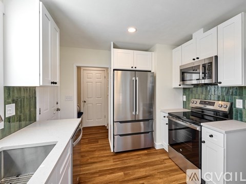 A kitchen with white cabinets and a stainless steel refrigerator.