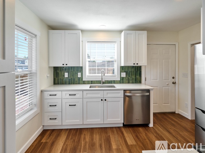 A kitchen with white cabinets and a wooden floor.